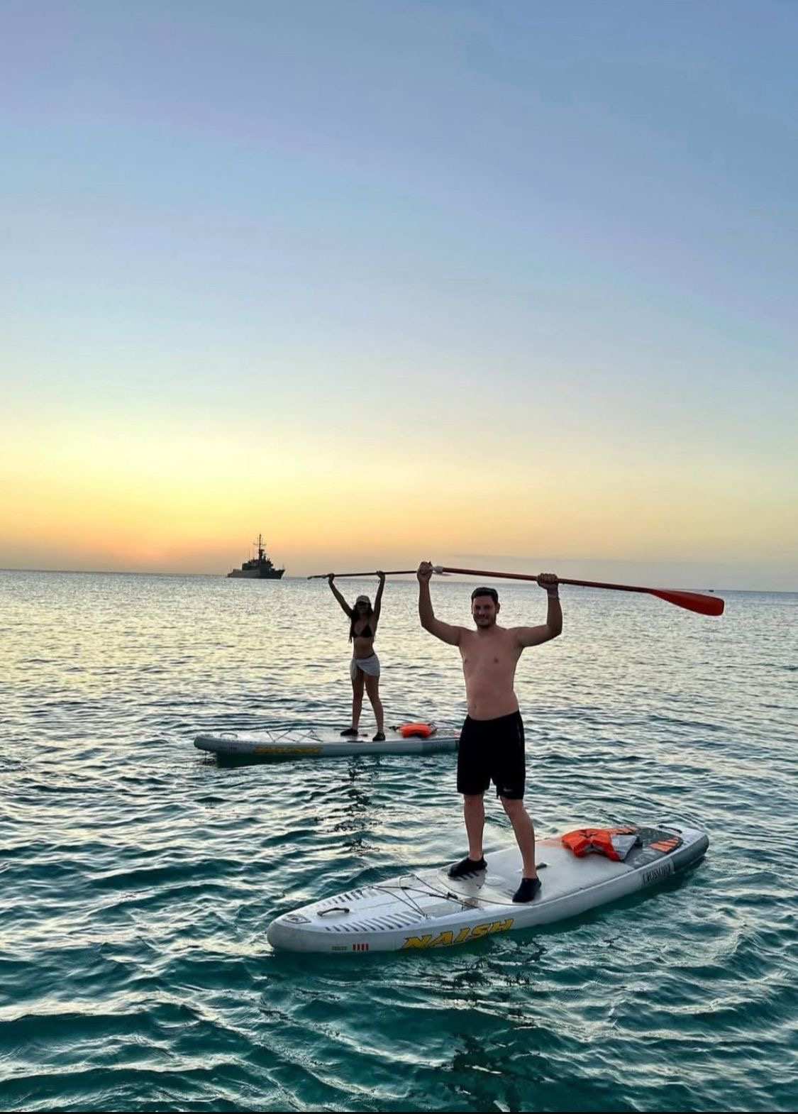 Amigos posando sobre paddle boards al ocaso