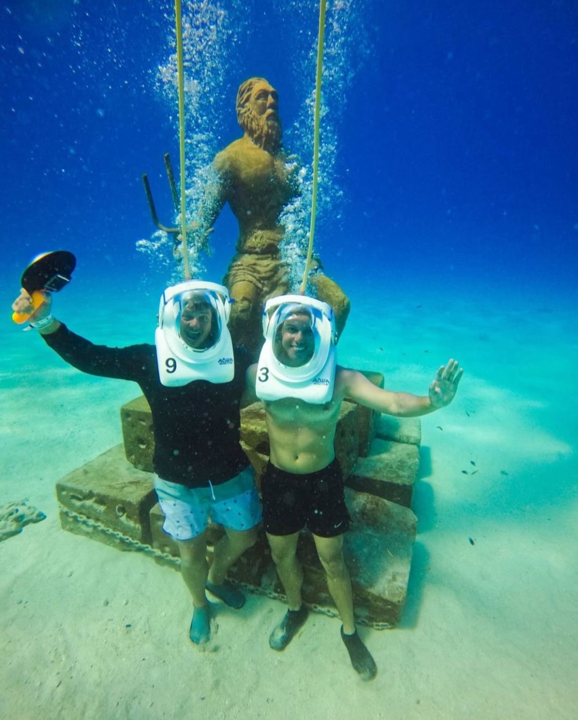 Pareja de aquanautas junto a la estatua de Neptuno